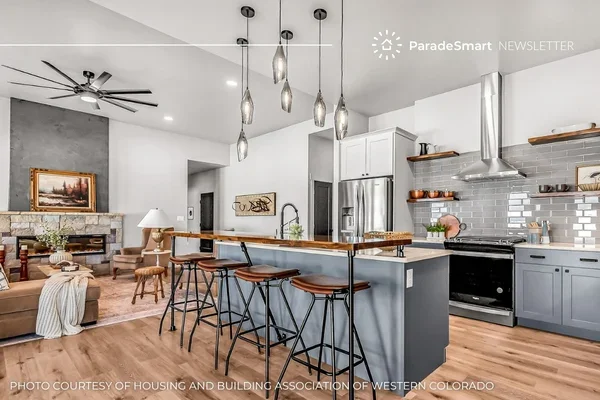 A styled Parade of Homes kitchen with a waterfall-edge island, pendant lighting, and stainless steel appliances