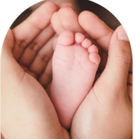 A newborn's foot cradled in her parents' hands