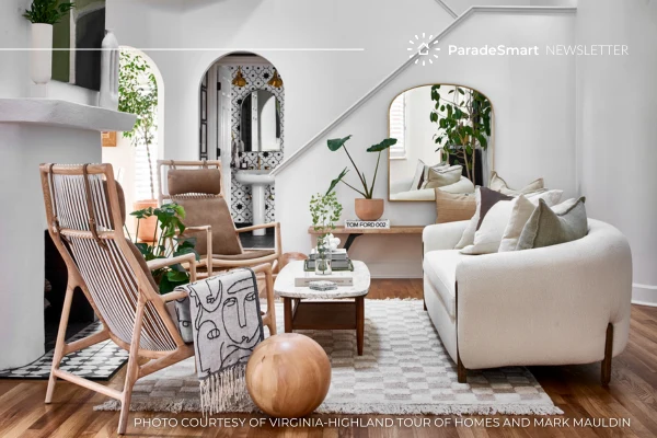 A styled Parade of Homes living room with woven lounge chairs, a stone fireplace, and layered neutral textiles